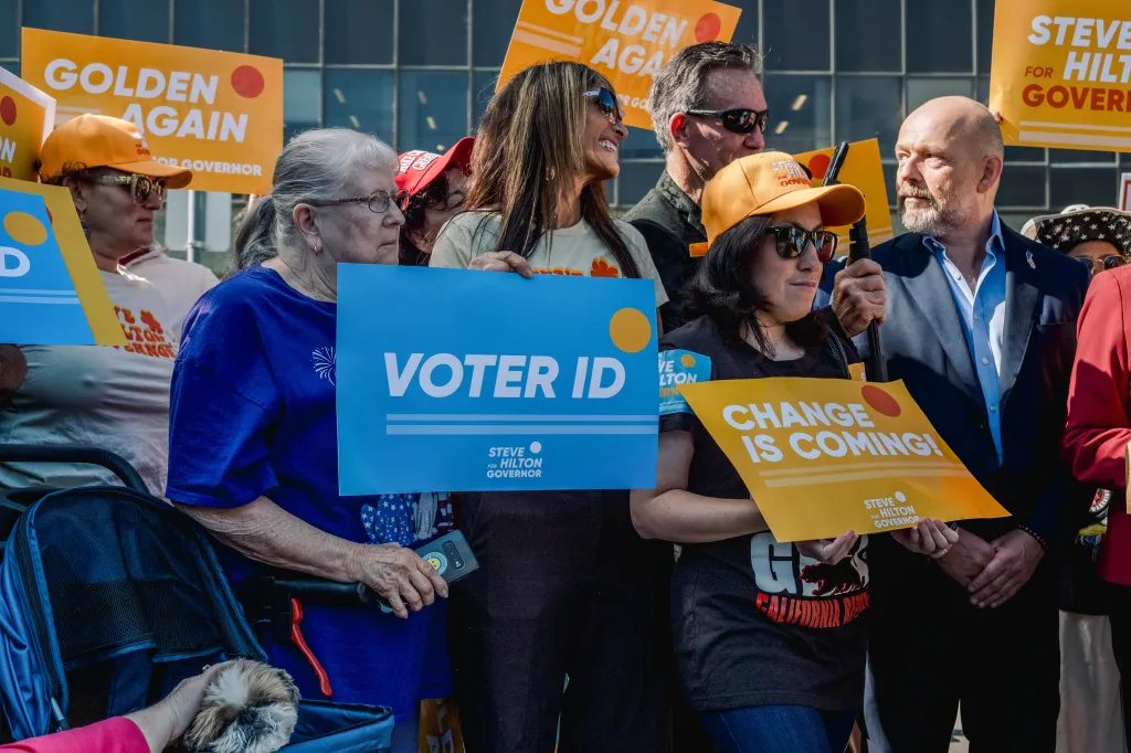 Attendees at a news conference hold "Voter ID" signs in support of Steve Hilton for California Governor.