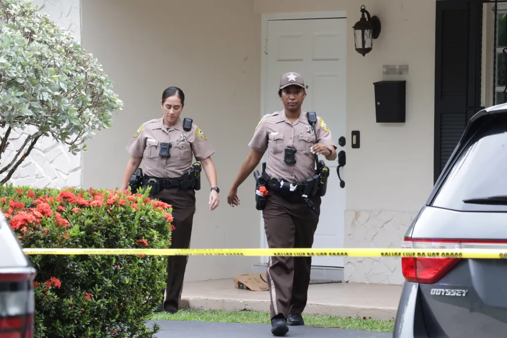Two Miami-Dade County Sheriff's deputies walk around a yellow 