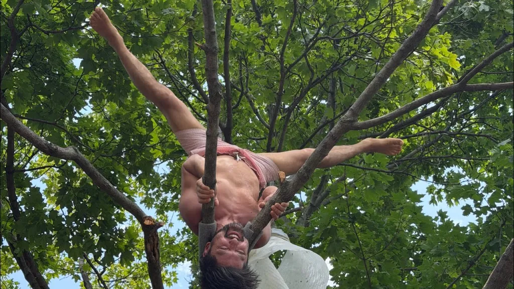 Galymzhan Abaildayev, 44, hanging upside down from a tree.