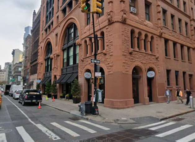 Corner view of 484-490 Broome St. in Soho, a Romanesque Revival red-brick structure featuring broad arches and ornate terra-cotta details.