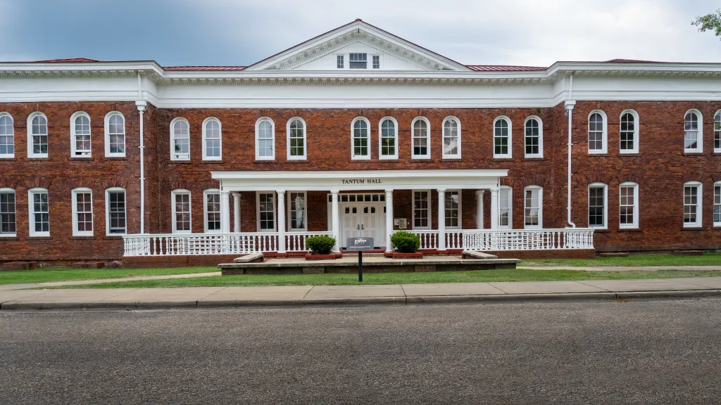 Tantum Hall, a brick building with white trim, arched windows on the second floor, and a white-columned porch, at Tuskegee University.