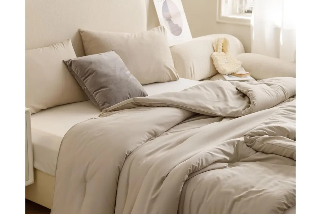 A bed with a light grey comforter and matching pillows