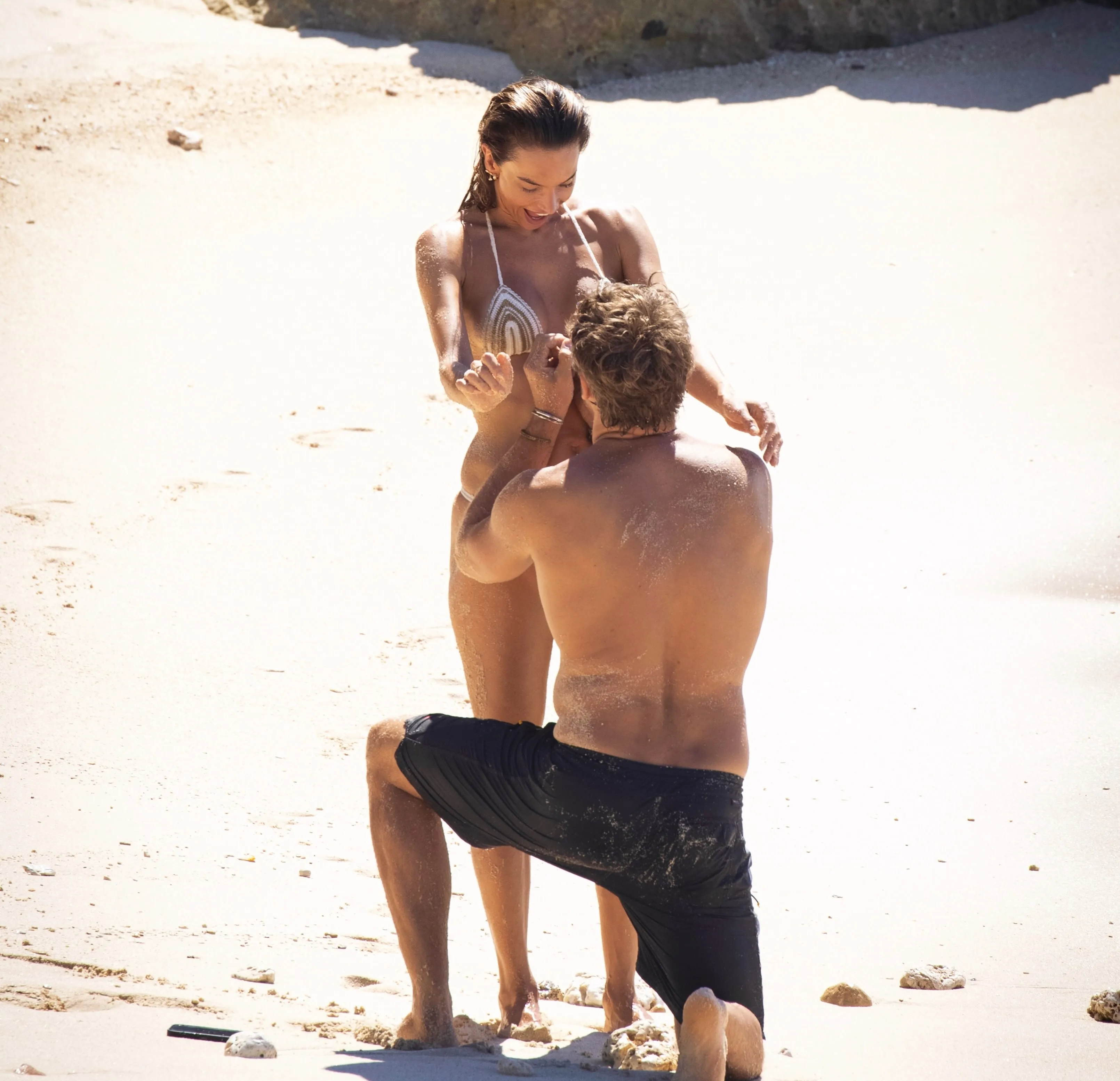 Buck Palmer proposing to Alessandra Ambrosio on a sandy beach.