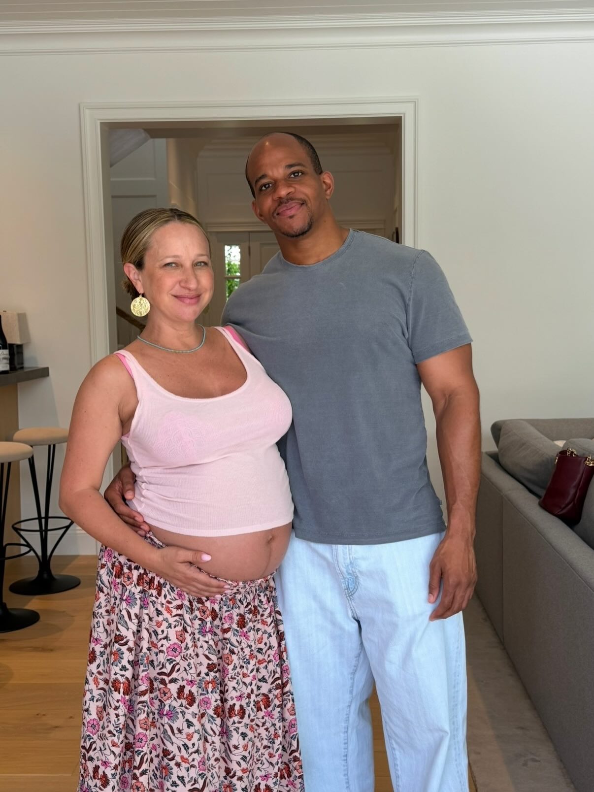 Jennifer Meyer and Geoffrey Ogunlesi posing, with Meyer holding her pregnant belly.