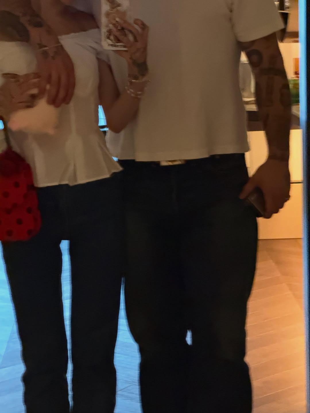 Ariana Grande's arm around Ricky Alvarez's waist, both wearing dark pants and light tops.