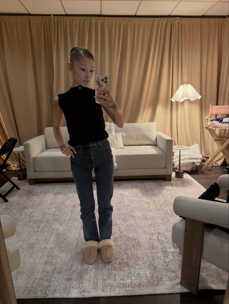 Ariana Grande posing for a mirror selfie in a casual outfit.