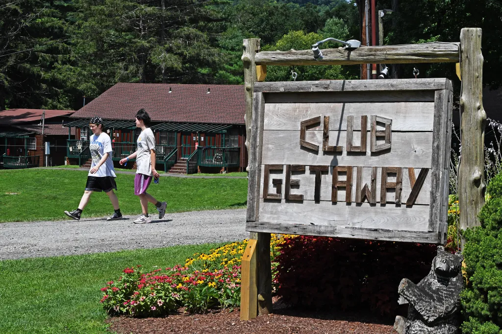 The "Club Getaway" sign in the foreground, with two women walking on a path in the background.