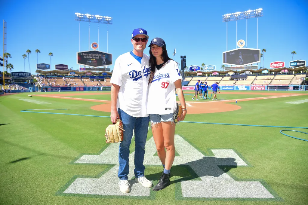 A man and a woman in Dodgers jerseys on the field at Dodger Stadium.
