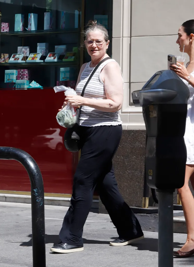 Bridget Fonda out to lunch in Los Angeles, wearing a striped tank top, black trousers, and sneakers.