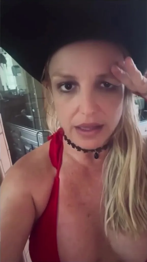 Britney Spears with one eye droopy and one hand touching her forehead, speaking about a botched Botox procedure.