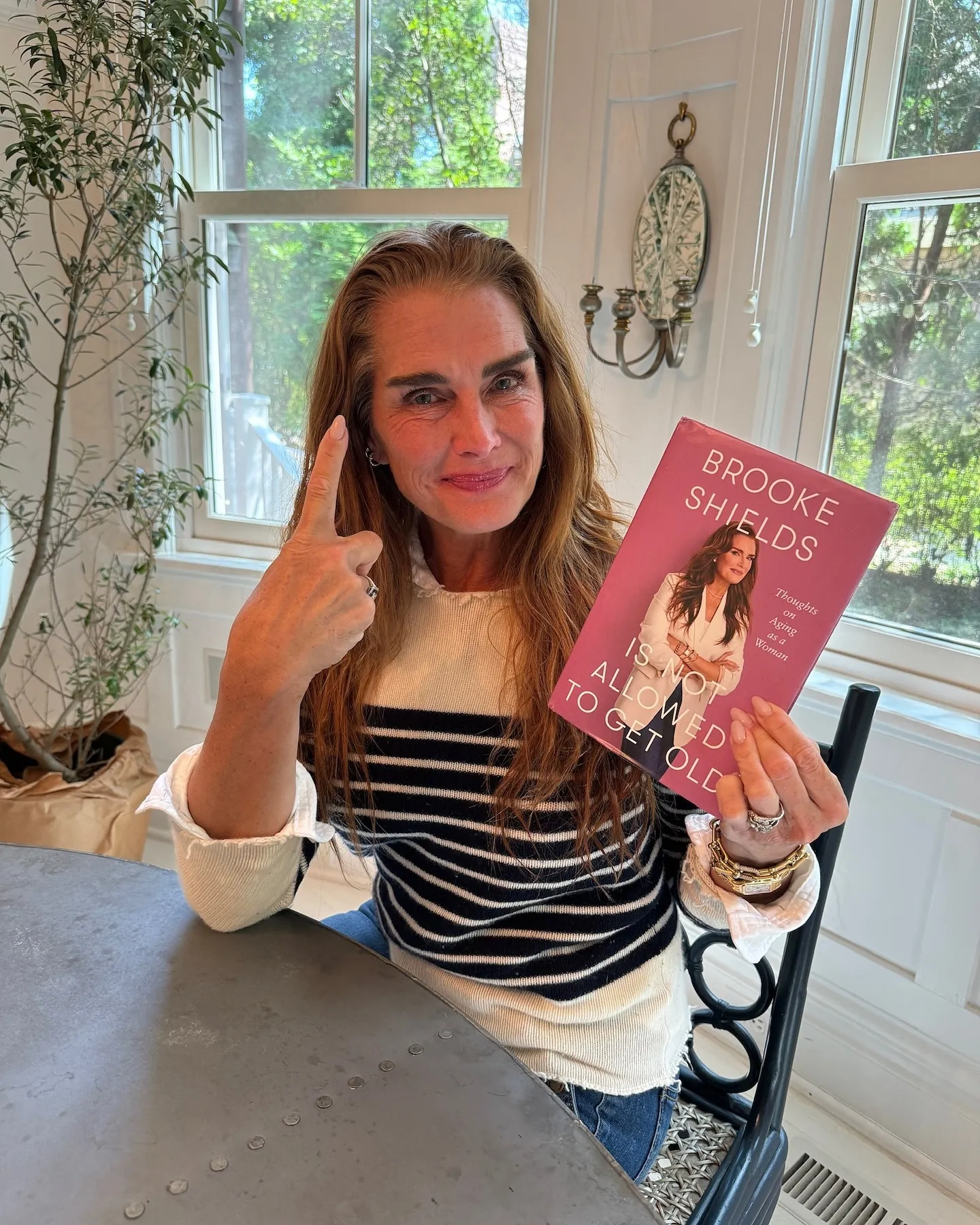 Brooke Shields holding her new book, "Brooke Shields Is Not Allowed to Get Old."