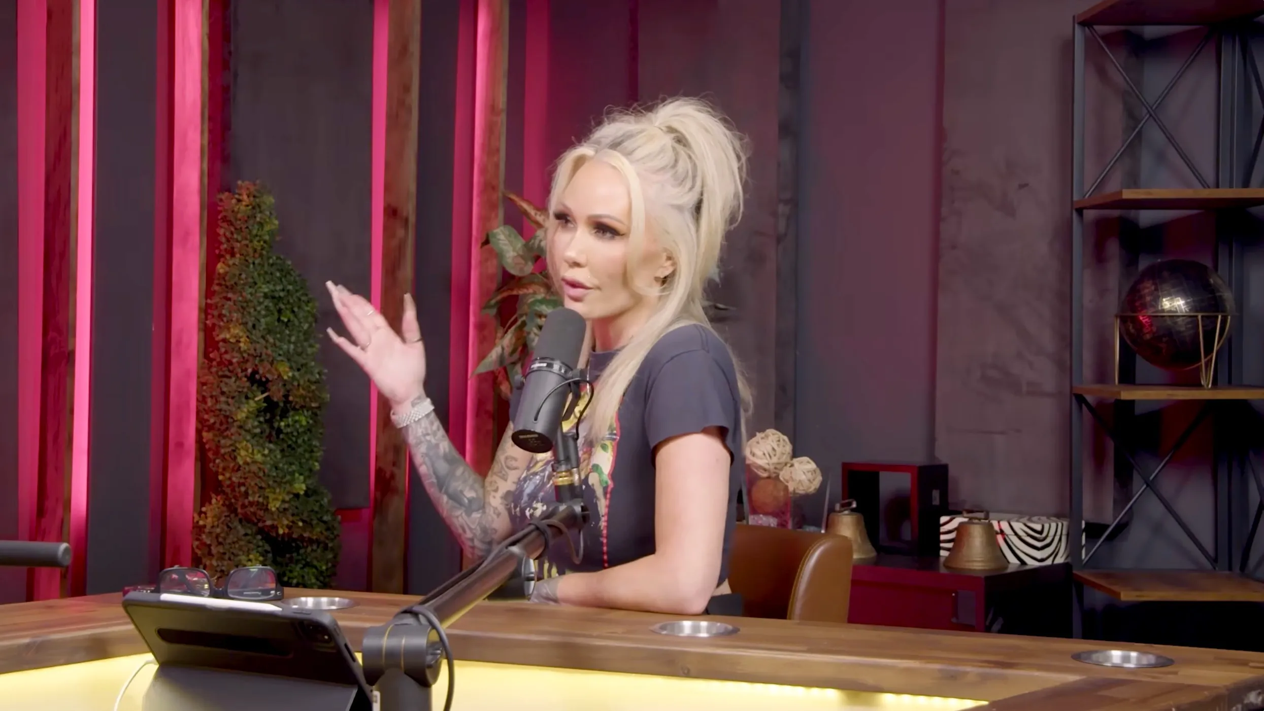 Bunnie Xo talking into a microphone at a podcast table.