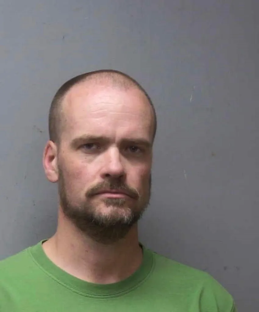 Mugshot of Christian Parmalee Edwards, a bald man with a beard and mustache wearing a green shirt.