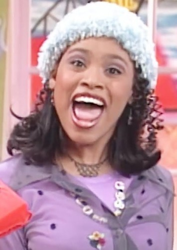 Christy Knowings with her mouth open, wearing a light blue knit hat and a purple top.