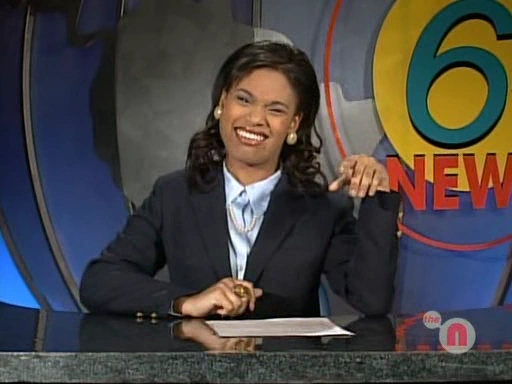 Christy Knowings as a news anchor at a desk.