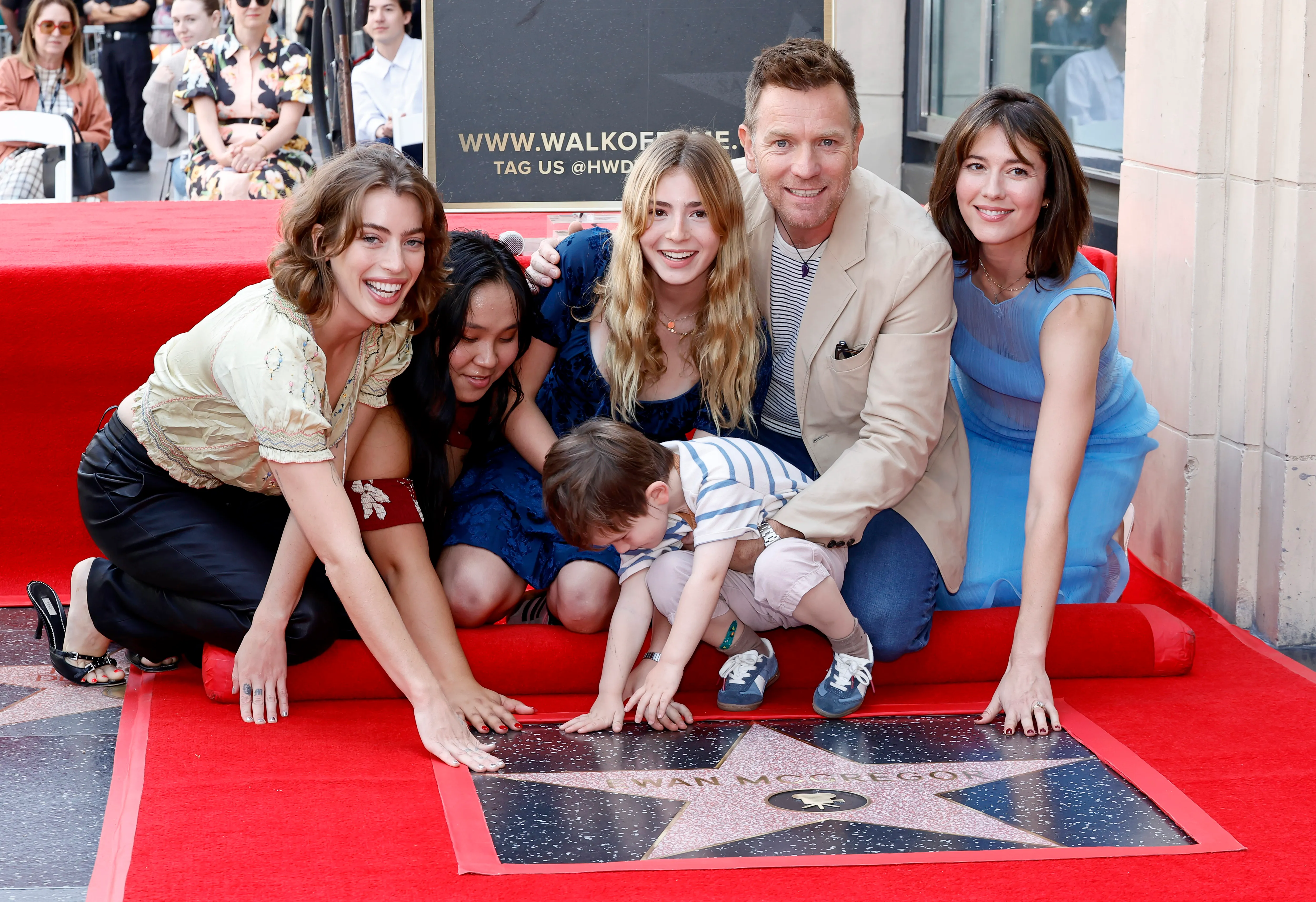 Clara McGregor, Jamyan McGregor, Anouk McGregor, Laurie McGregor, Ewan McGregor, and Mary Elizabeth Winstead kneeling on a red carpet next to Ewan McGregor's newly unveiled star on the Hollywood Walk of Fame.