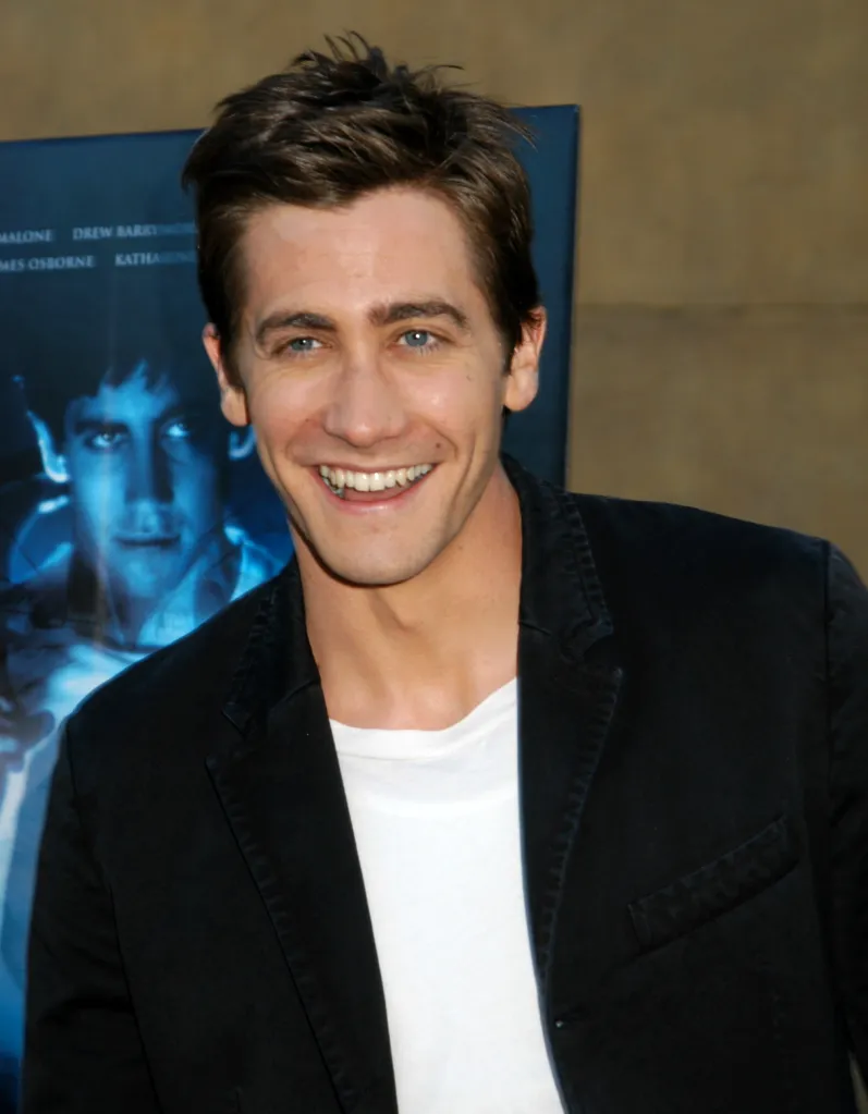 Jake Gyllenhaal smiling in front of a movie poster for 