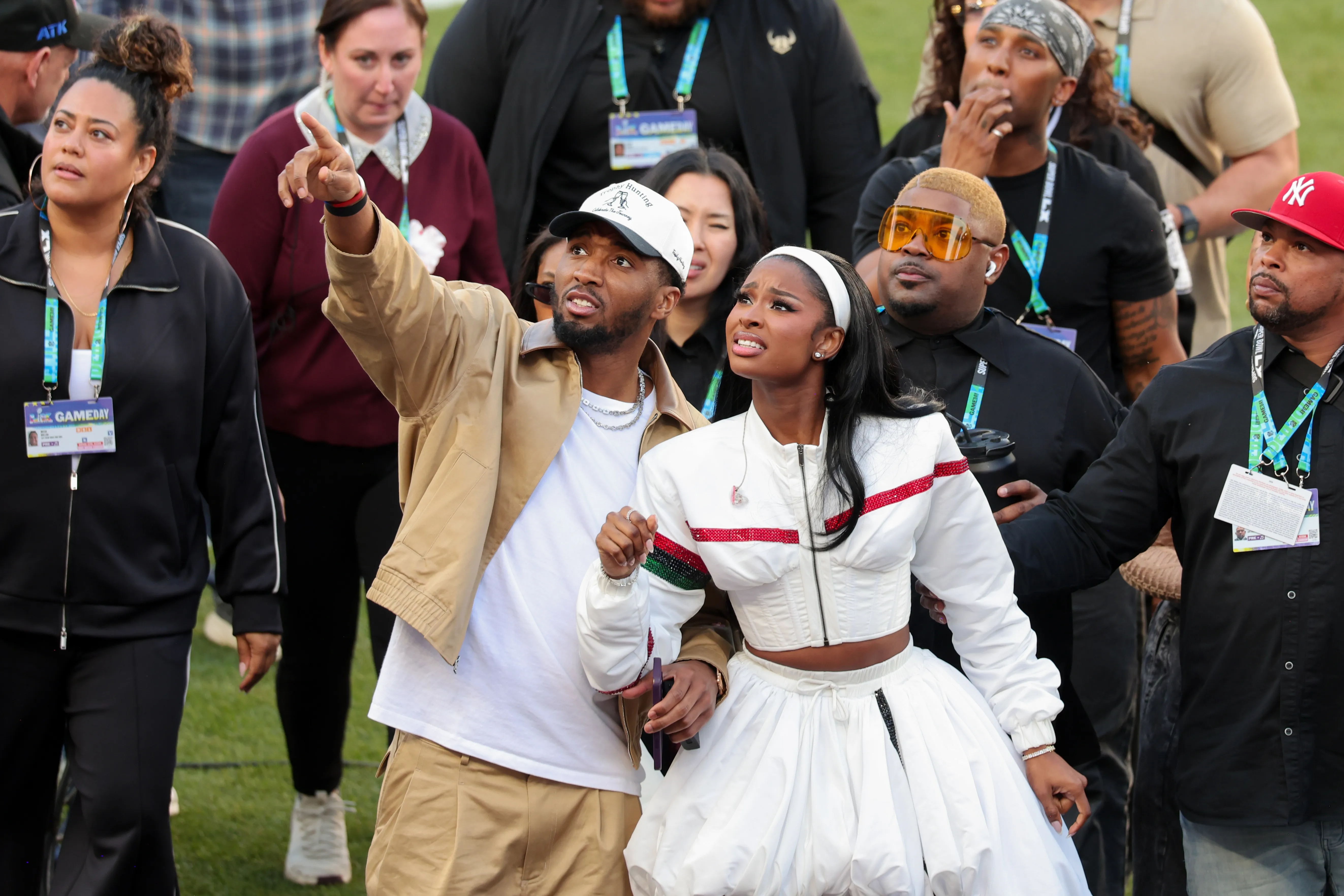 Donovan Mitchell points into the distance as he walks with Coco Jones at Super Bowl LX.