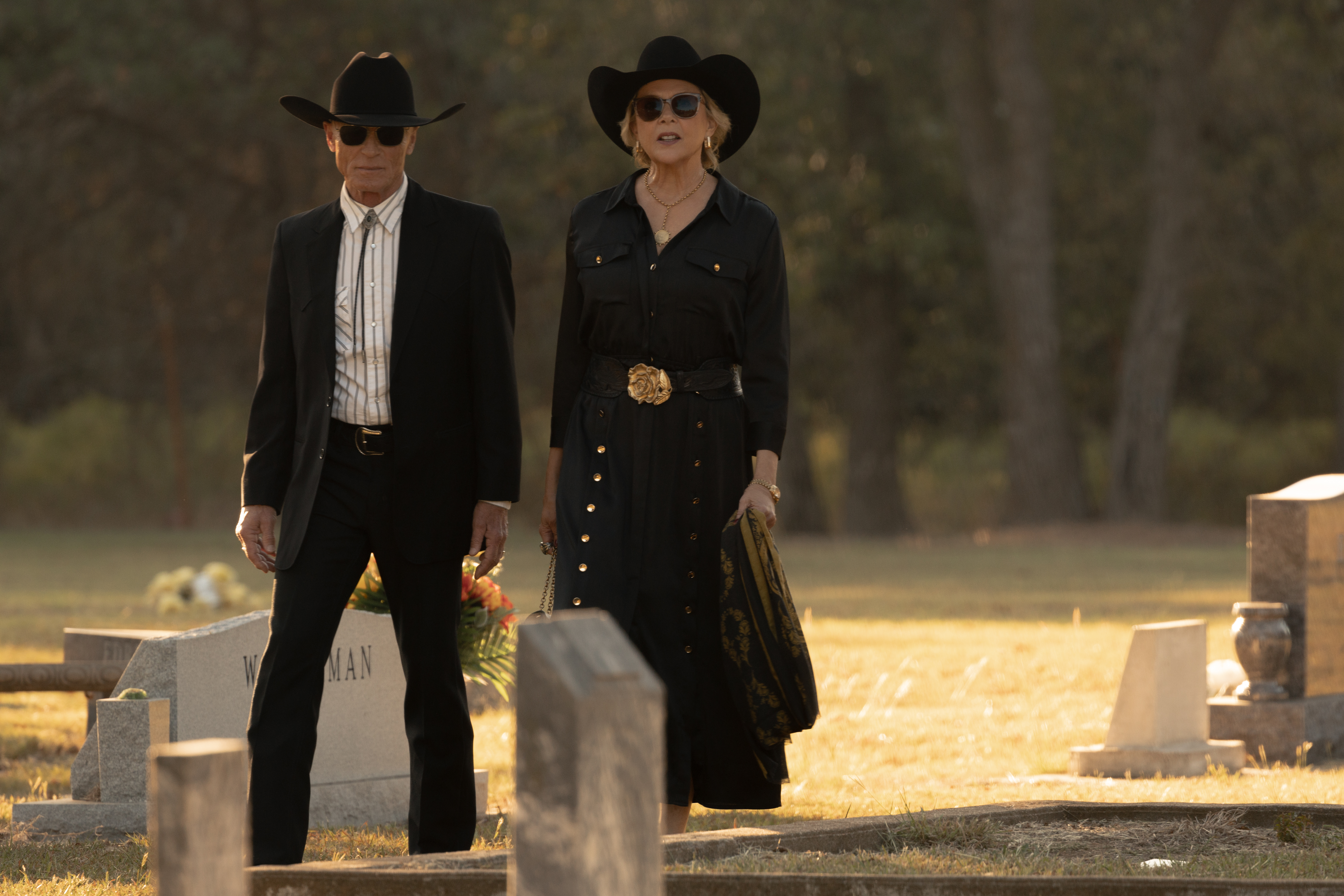 Ed Harris as Everett McKinney and Annette Bening as Beulah Jackson, both wearing black cowboy attire and sunglasses, stand in a cemetery.