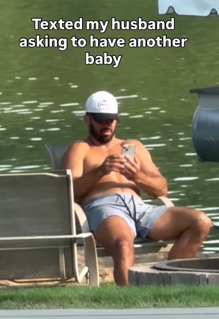 A shirtless Eric Decker, wearing a white baseball cap and blue shorts, sits by a lake, looking at his phone with a shocked expression, with overlaid text "Texted my husband asking to have another baby".