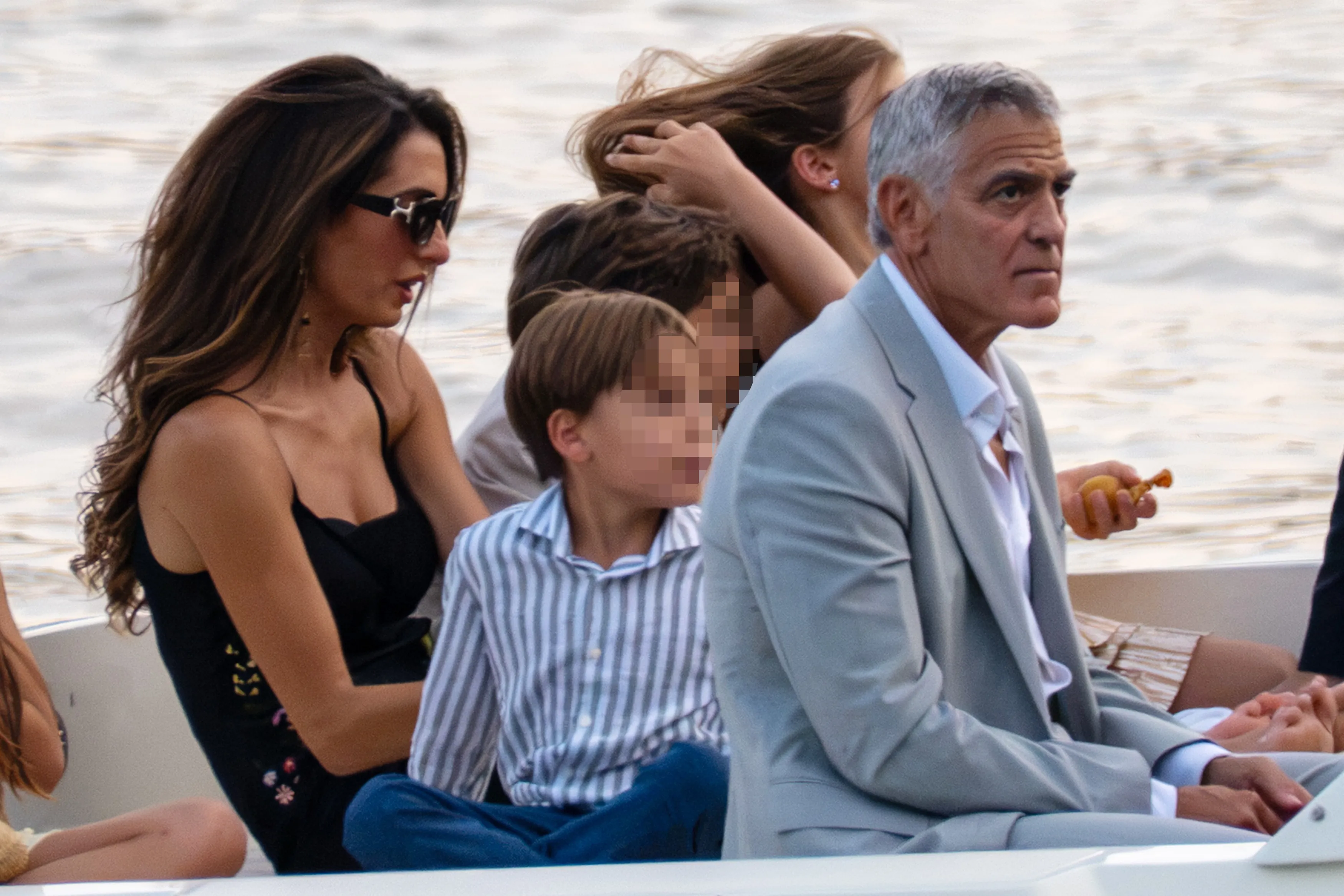 George and Amal Clooney with their children, Ella and Alexander, on a boat.