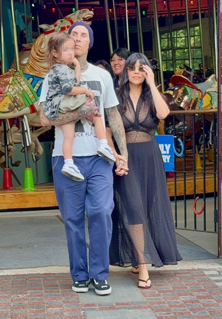 Travis Barker carrying his son Rocky, while holding hands with Kourtney Kardashian as they leave the Central Park Carousel.