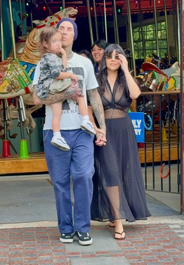 Travis Barker carrying his son Rocky, while holding hands with Kourtney Kardashian, leaving the Central Park Carousel.