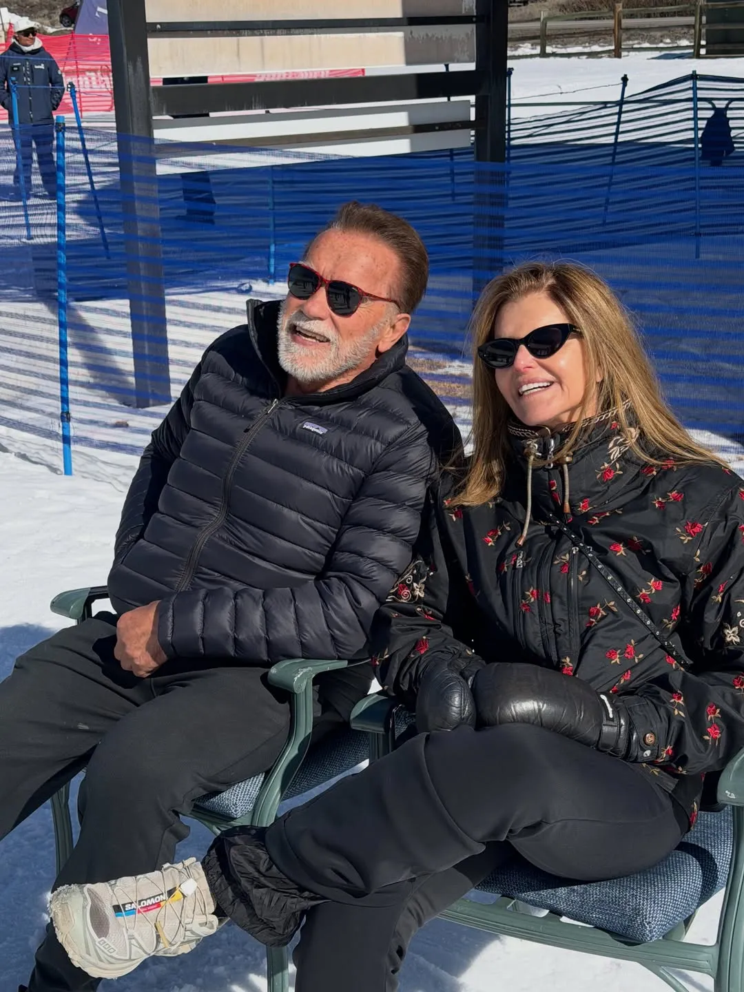 Arnold Schwarzenegger and Maria Shriver sitting next to each other on a ski slope.
