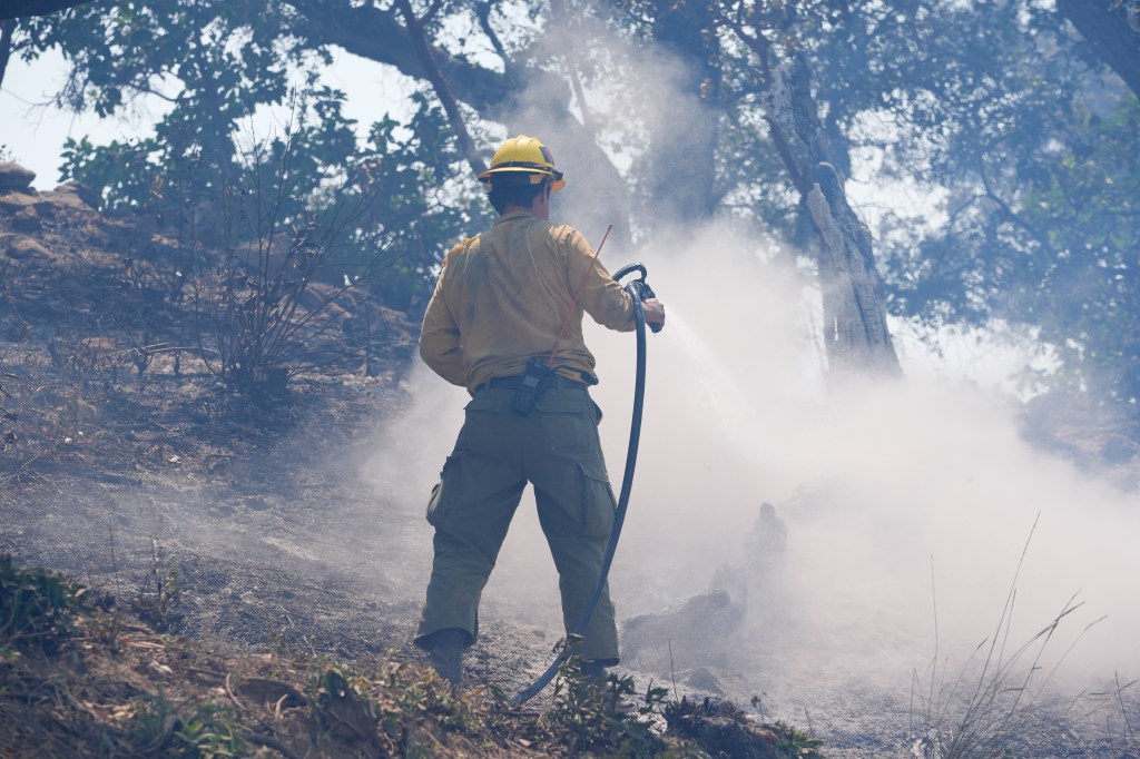 A firefighter battling flames and smoke from the Timber Fire wildfire in Big Sur, California.