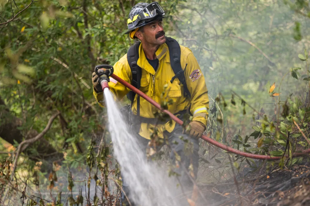 A firefighter sprays water from a hose on a hotspot from the Timber Fire.
