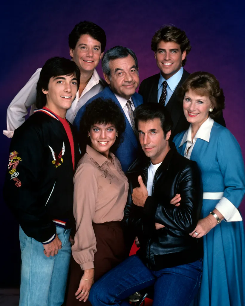 A group portrait of the cast of "Happy Days" including Scott Baio, Anson Williams, Erin Moran, Tom Bosley, Henry Winkler, Ted McGinley, and Marion Ross.