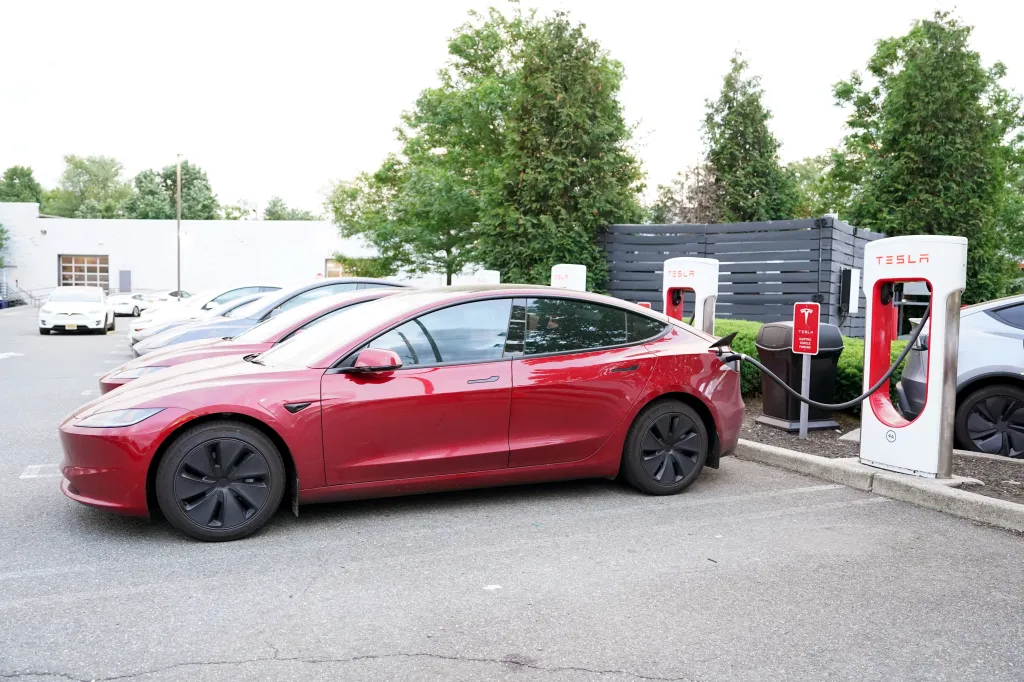 A red Tesla Model S charging at a Tesla Supercharger station at a dealership in Paramus, NJ.