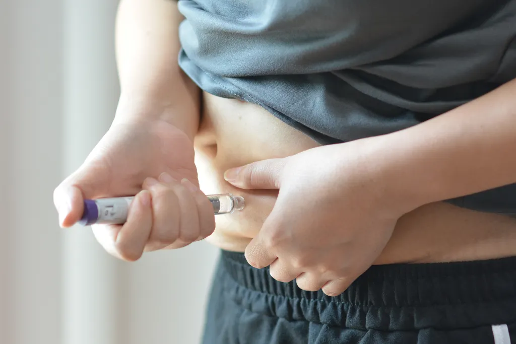 A person injecting an insulin pen into their stomach for diabetes or weight loss treatment.