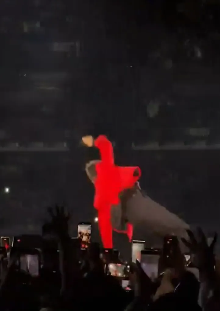 Harry Styles in a red jumpsuit slipping on stage.