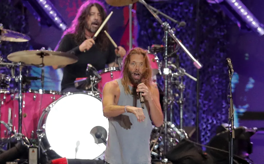 Taylor Hawkins singing into a microphone with Dave Grohl playing drums behind him at Lollapalooza 2022.