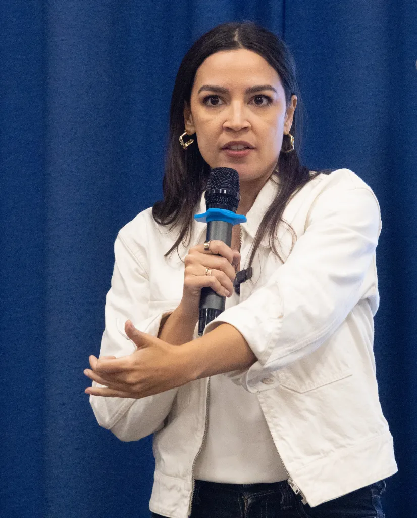 Rep. Alexandria Ocasio-Cortez speaking into a microphone at a town hall.