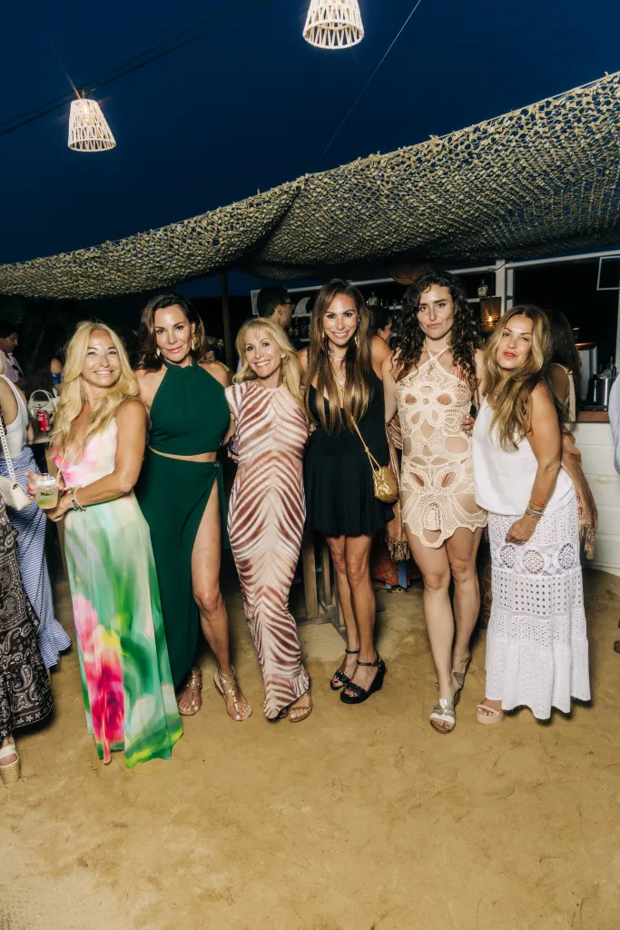Six women posing together at an outdoor party.