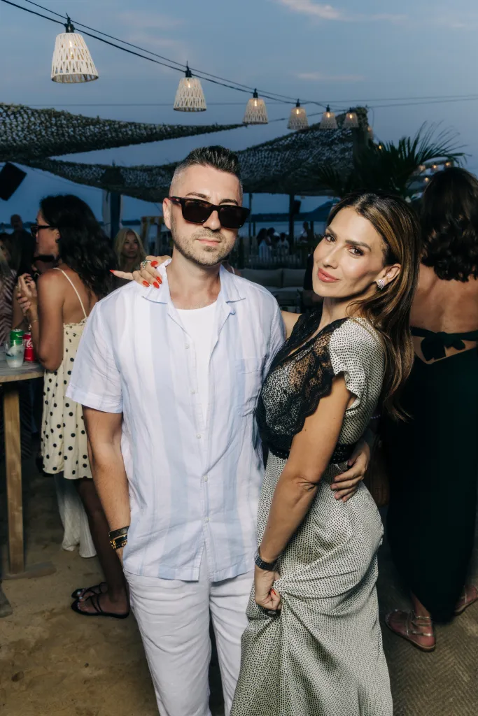 A man in sunglasses and a woman in a black and white dress posing together.