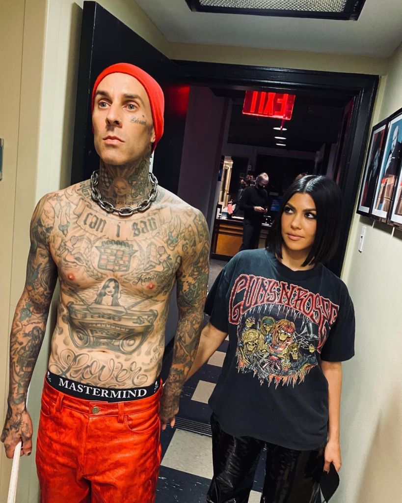 Travis Barker and Kourtney Kardashian holding hands.