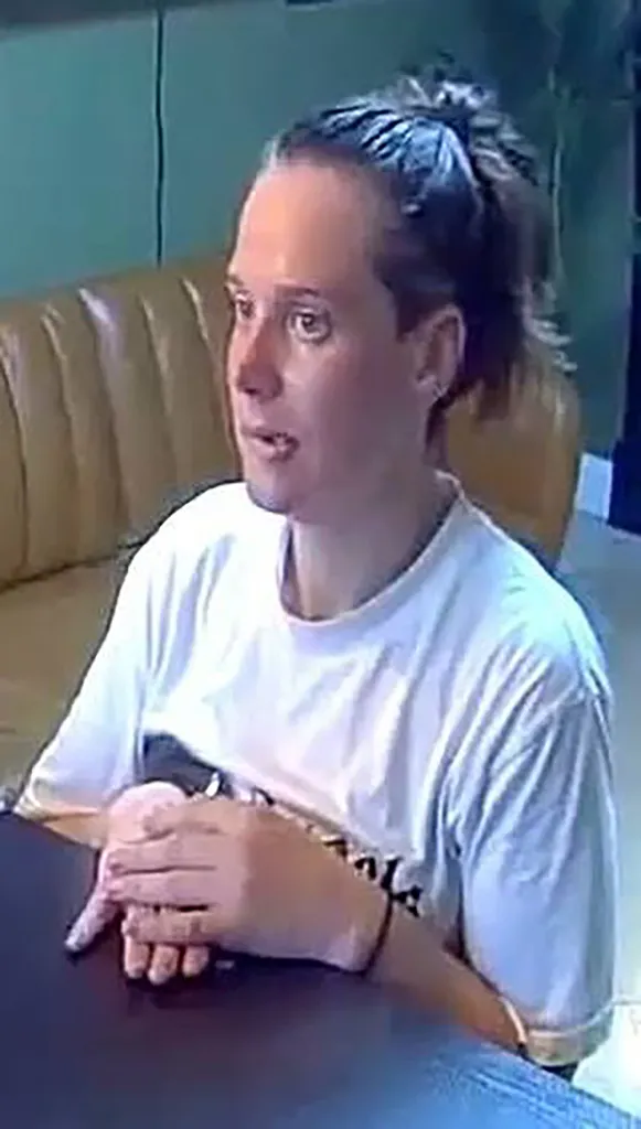 Isabelle Rose Johnson, a 38-year-old woman with her hair pulled back, wearing a white t-shirt, sits at a table.