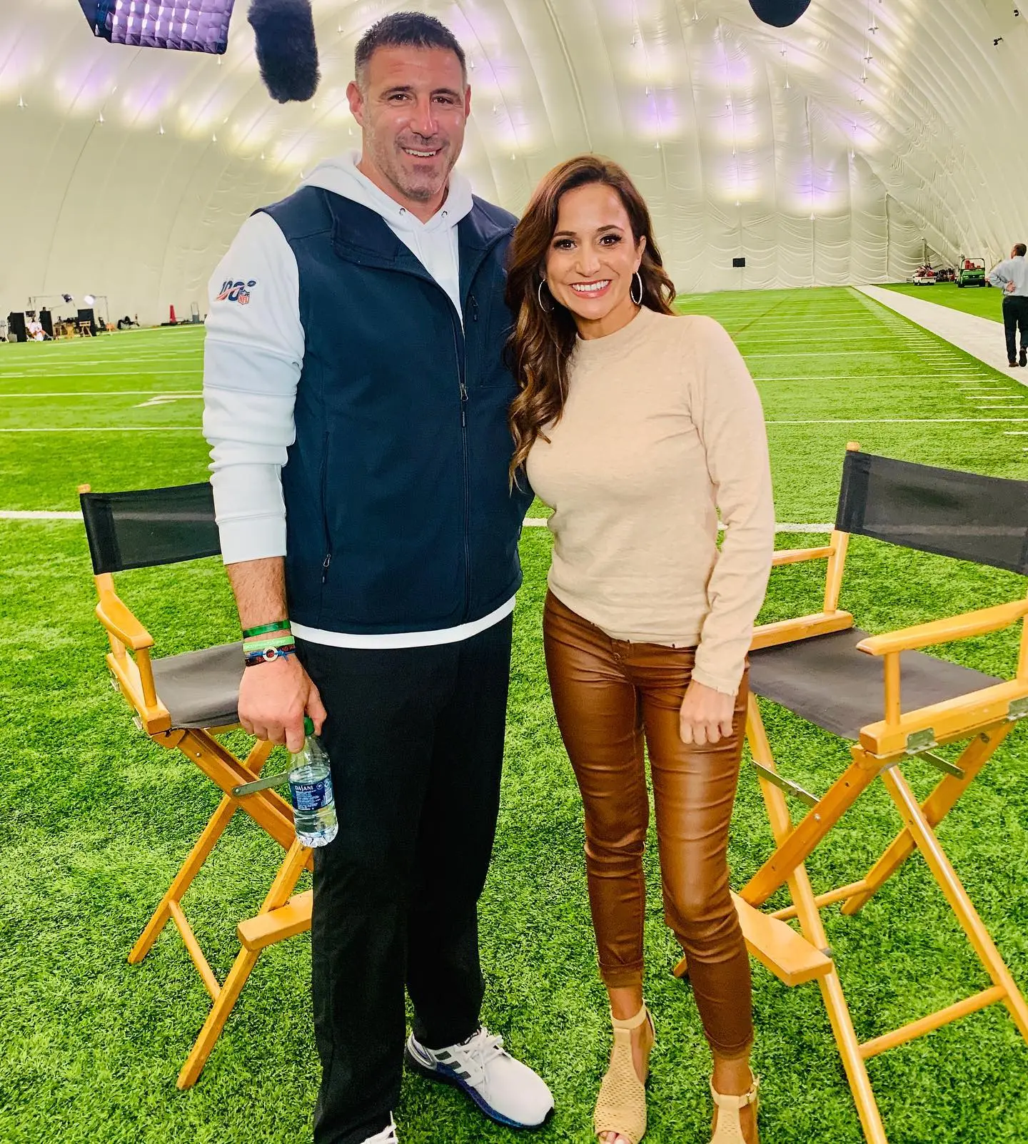 Mike Vrabel and Dianna Russini standing on a football field.