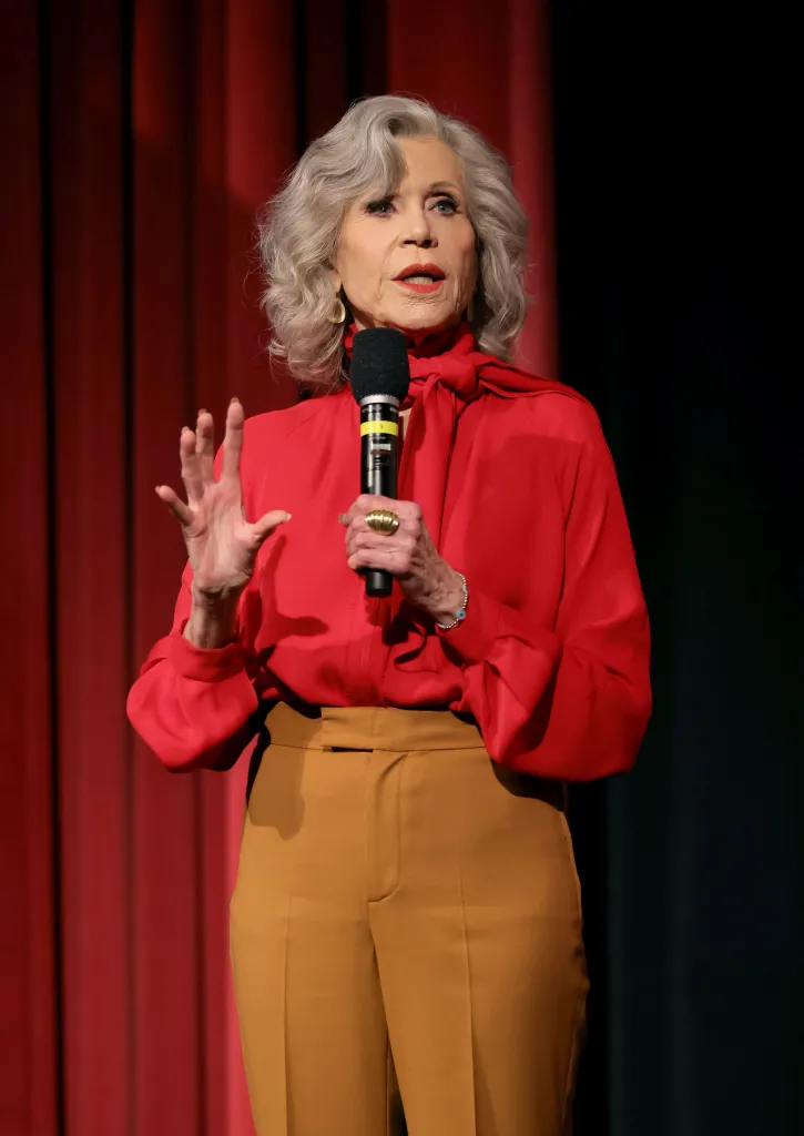 Jane Fonda speaking at the Hollywood Climate Summit, holding a microphone.