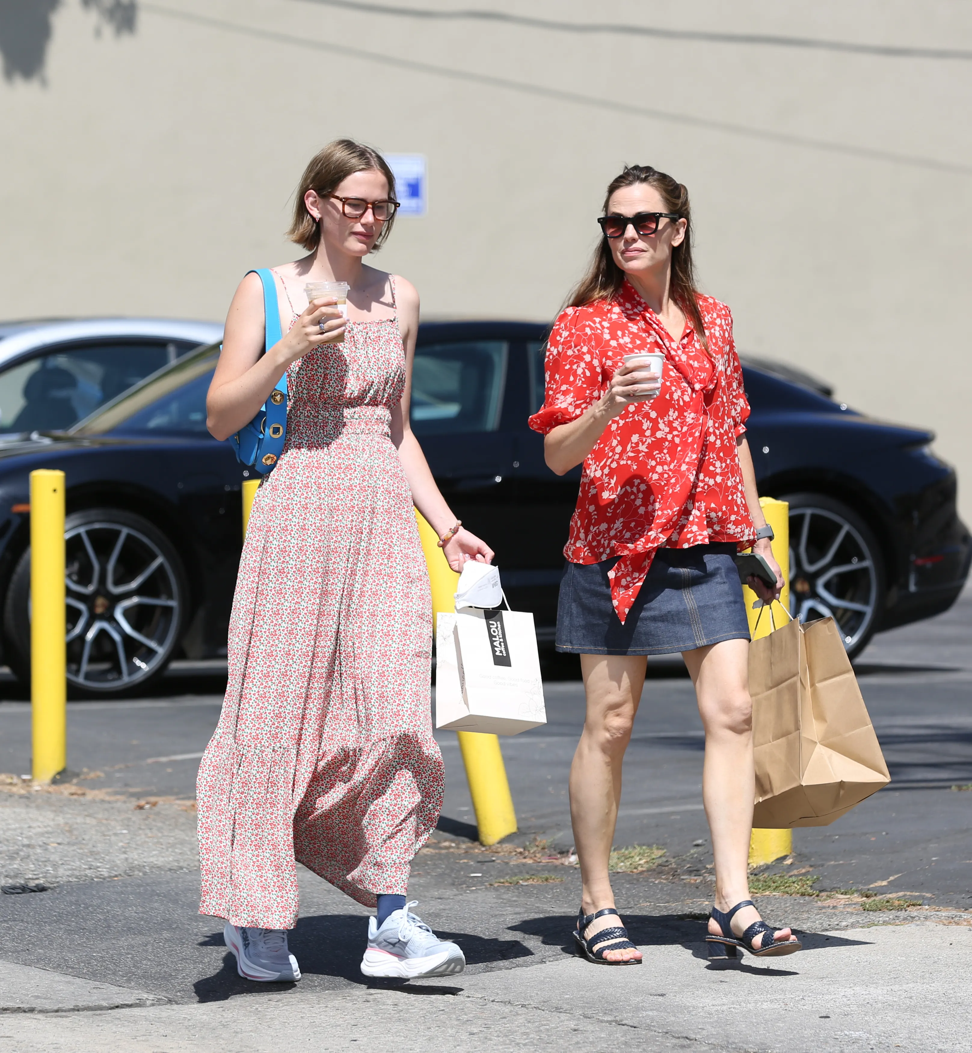 Violet Affleck and Jennifer Garner walking together, carrying drinks and shopping bags.