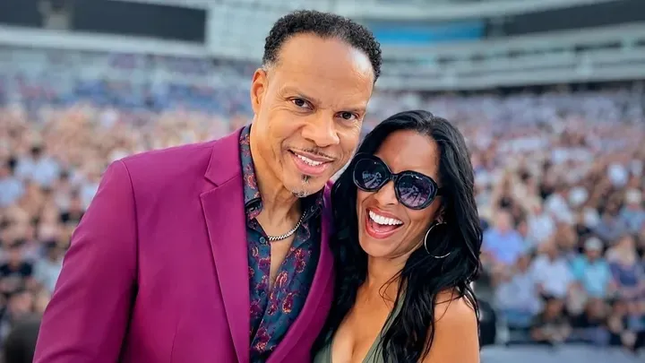 John Paris of Earth, Wind & Fire and his wife, Kathy, smiling with a crowd in the background.