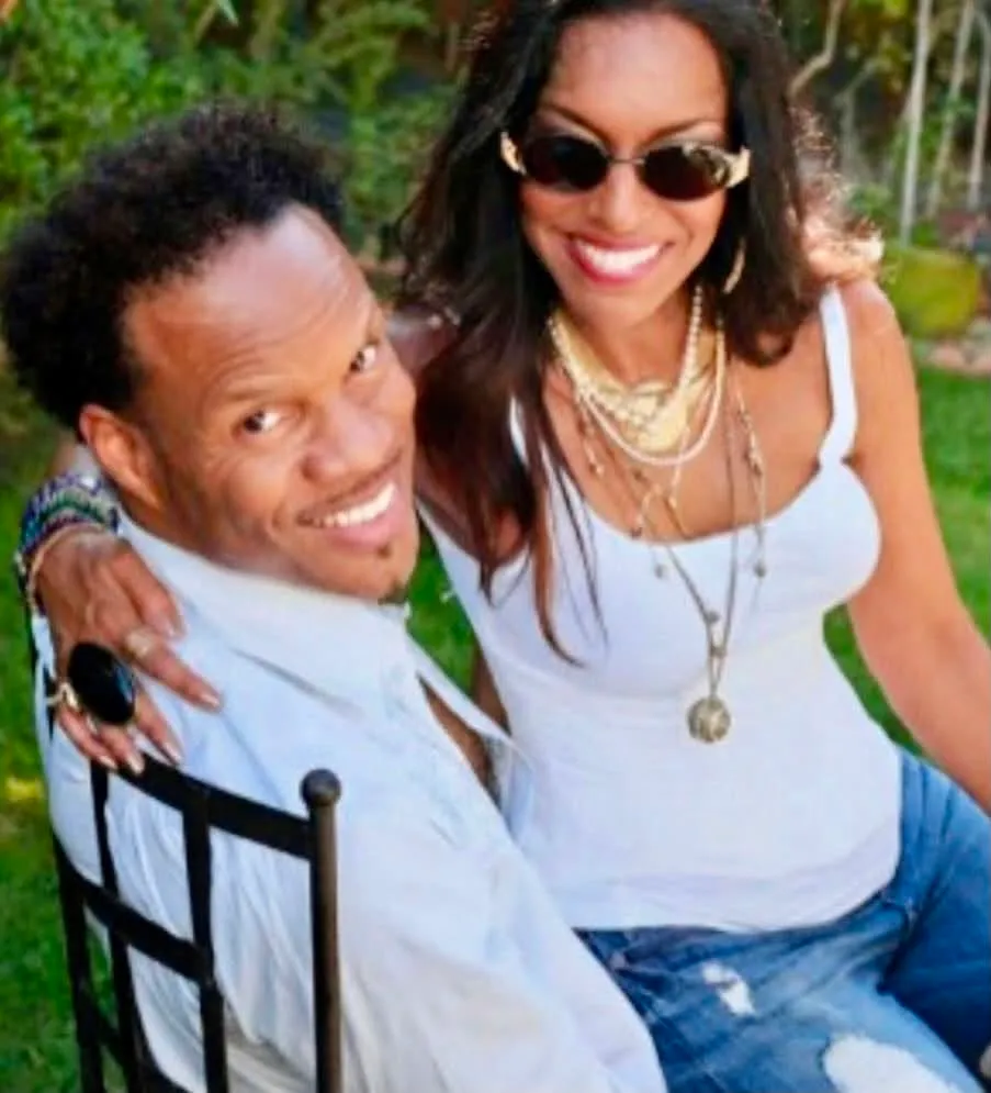 John Paris of Earth, Wind & Fire smiles at the camera with a woman sitting next to him.