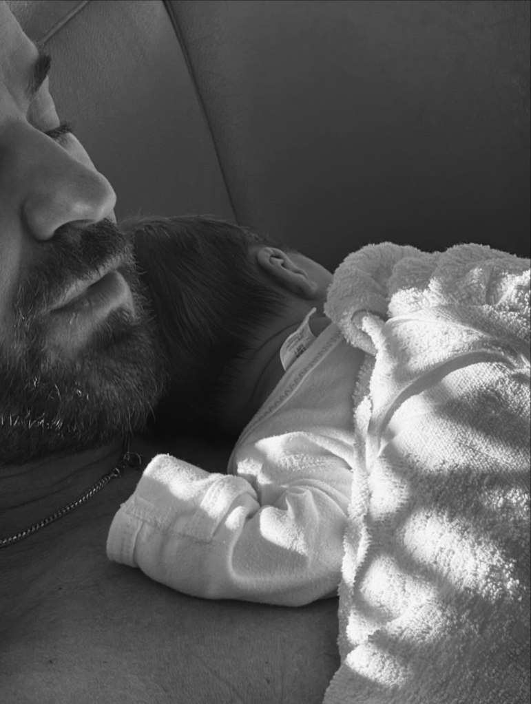 Justin Theroux with a baby sleeping on his chest.