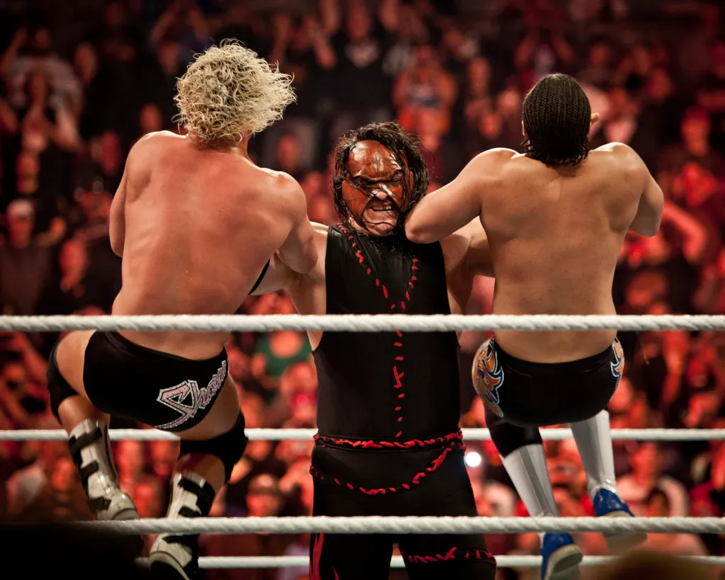 Kane holds two top stars in a WWE ring.