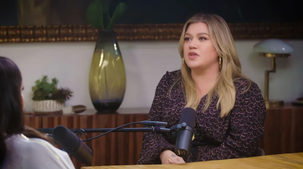 Kelly Clarkson speaking into a microphone.
