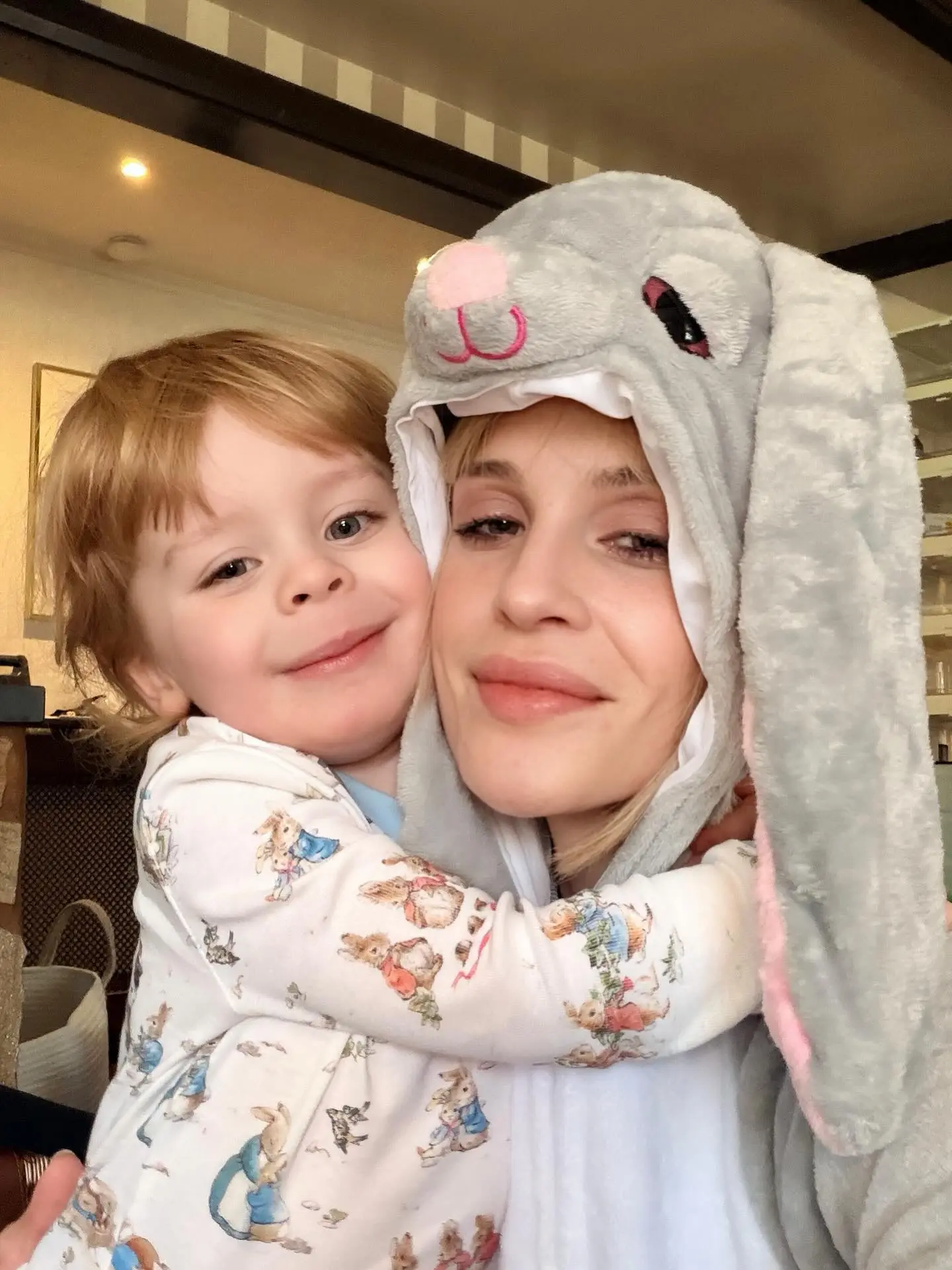 Kelly Osbourne wearing a bunny costume, hugging a child in Peter Rabbit pajamas.