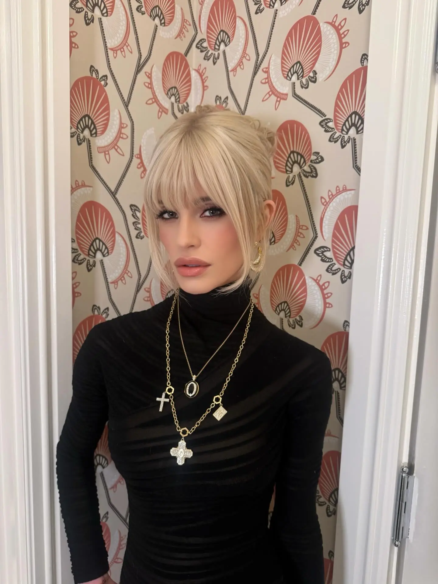 Kelly Osbourne in a black turtleneck and multiple gold necklaces.